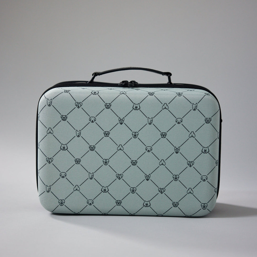 ZUXI hard-shell travel case in light sage green with a repeating dog-face diamond print pattern and black zippered trim and handle, photographed against a plain gray background.