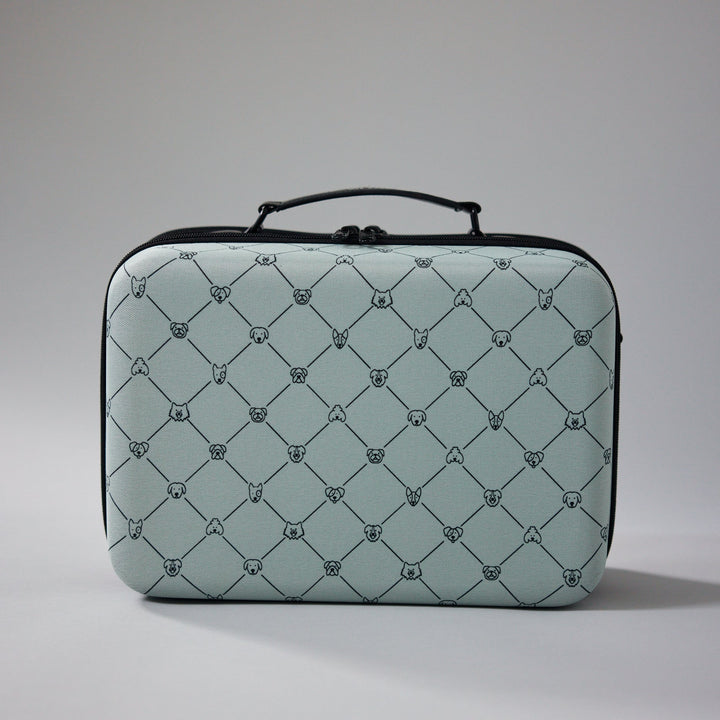ZUXI hard-shell travel case in light sage green with a repeating dog-face diamond print pattern and black zippered trim and handle, photographed against a plain gray background.