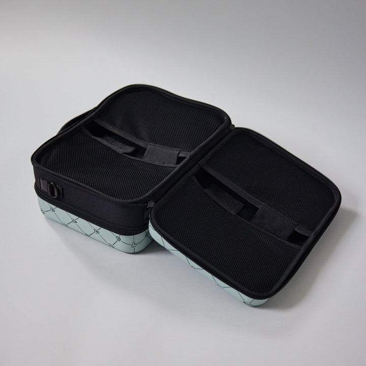 Open ZUXI travel case in sage green diamond print fabric with a black interior showing elastic straps and mesh compartments for organizing dog care items.