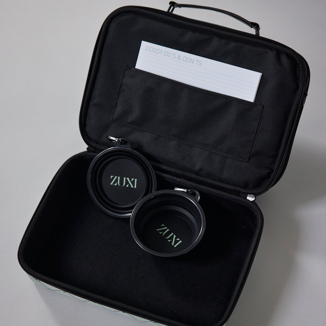Open black ZUXI travel case showing two nested collapsible black travel bowls with the ZUXI logo, and a "Doggy Do's & Don'ts" card tucked into the interior pocket.